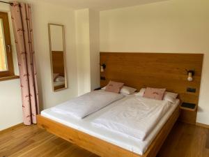 een slaapkamer met een groot bed met een houten hoofdeinde bij Seebach Chalets in Scheffau am Wilden Kaiser