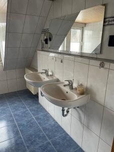 La salle de bains est pourvue de 2 lavabos et d'un miroir. dans l'établissement FeWo Rennsteigschloß, à Benshausen
