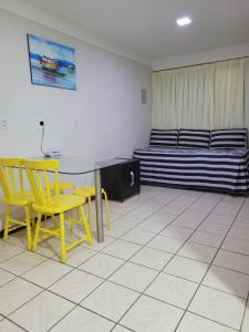 een kamer met gele stoelen, een tafel en een bed bij Flat da Praia Natal in Natal