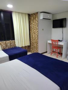 een hotelkamer met 2 bedden, een bureau en een stoel bij Flat da Praia Natal in Natal