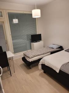 a bedroom with two beds and a table and a window at Bright studio apartment on the 6th floor in Kerava