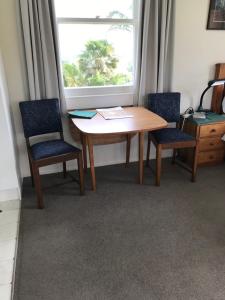 a wooden table with two chairs and a window at Tui Cottage in Te Arai