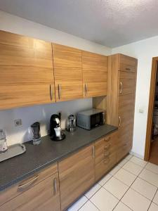 eine Küche mit Holzschränken und einer Mikrowelle in der Unterkunft Komplettes Apartment - 2 Zimmer Wohnung in Kehl am Rhein