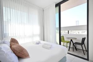 1 dormitorio blanco con 1 cama, mesa y sillas en Summer White by HolyGuest en Tel Aviv