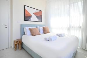 a bedroom with a large white bed with towels on it at Summer White by HolyGuest in Tel Aviv