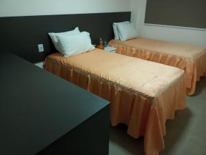 Habitación con 2 camas con sábanas de color naranja en Ondas de Itacimirim, o paraíso é aqui! Pé na areia, en Itacimirim