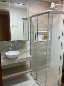 La salle de bains est pourvue d'un lavabo et d'une douche en verre. dans l'établissement Ondas de Itacimirim, o paraíso é aqui! Pé na areia, à Itacimirim