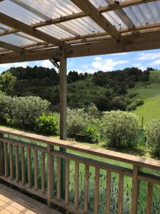 a wooden deck with a view of a field at Tui Cottage in Te Arai