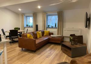 ein Wohnzimmer mit einem braunen Sofa und gelben Kissen in der Unterkunft Hotel Rosenhof GmbH in Ramstein-Miesenbach