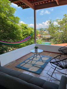 eine Terrasse mit einer Hängematte und einem Tisch auf einer Veranda in der Unterkunft Villa Coiros Bici, Hospedaje y Bienestar in Municipio Tonatico