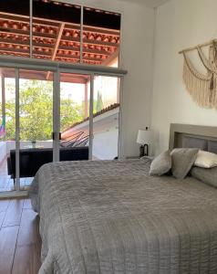 ein Schlafzimmer mit einem Bett und einem großen Fenster in der Unterkunft Villa Coiros Bici, Hospedaje y Bienestar in Municipio Tonatico