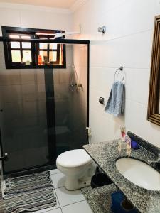 y baño con ducha, aseo y lavamanos. en Casa familiar en Arraial do Cabo