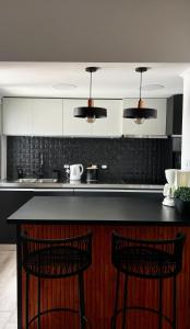 a kitchen with a black counter and two bar stools at Casa Atilio -Dpto Premium con entrada autónoma in Rafaela