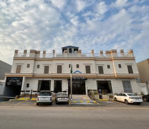 リヤドにあるهوتيلتن قرطبه HOTELTEN Qurtubahの前に車が駐車されている白い建物