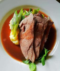 un plato de comida con un trozo de carne y salsa en Cuisinease, en Ollerton