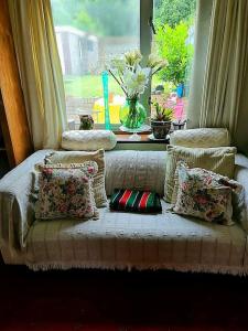 un sofá con almohadas sentado frente a una ventana en Cuisinease en Ollerton