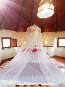 Cama blanca en habitación con lámpara de araña en The Windhouse en São Bartolomeu
