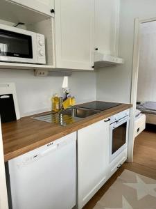 een witte keuken met een wastafel en een magnetron bij Apartment Mariankatu in Kokkola