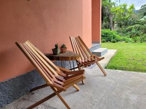 três cadeiras e uma mesa com uma planta num alpendre em Casa do Ipê - Hospedagem em Lumiar