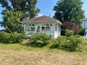 a small white house in a yard with bushes at Le Couvent in Sainte-Anne-des-Monts