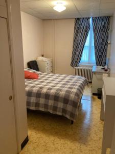 a bedroom with a bed with a checkered blanket at Le Couvent in Sainte-Anne-des-Monts
