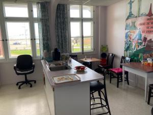 a kitchen with a counter and chairs and windows at Le Couvent in Sainte-Anne-des-Monts