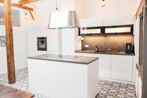 una cocina con armarios blancos y fregadero en HEIMATEL - Luxury Penthouse Loft, en Ravensburg