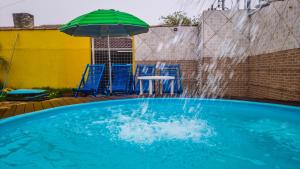 uma piscina com um guarda-sol verde e cadeiras e uma mesa em Pousada Portal em Chapada dos Guimarães