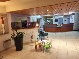 a restaurant with tables and chairs in a lobby at Hôtel Estuaire in Saint-Brevin-les-Pins