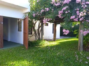 una casa con un árbol con flores rosas en el patio en La Blanquita del Tata, ideal para descansar!, en La Pedrera