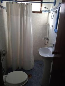 y baño con cortina de ducha blanca y aseo. en La Blanquita del Tata, ideal para descansar!, en La Pedrera