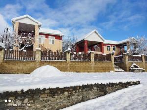 a fence in front of a house in the snow at Quba Guest House in Digah