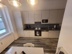 a kitchen with white cabinets and a wooden floor at Apartment Mohr am Semmering in Semmering