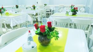 uma sala com mesas brancas e um vaso com rosas em Hotel Ipê em Belém