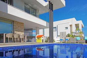 a swimming pool with chairs and a house at Villa Harmonia in Protaras