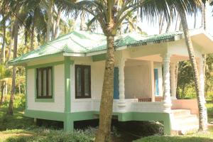 a small house with a palm tree in front of it at The Temple Tree Varkala in Varkala
