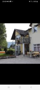 a building with a balcony and a table and benches at Rooms & Apartment Jozić in Prozor