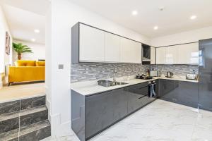 a kitchen with white and gray cabinets and a yellow couch at Eden Grove Holiday Retreat in Kirkby Thore