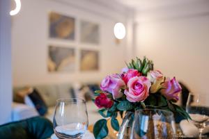 a vase filled with pink roses on a table with wine glasses at Bliss Land Luxury Apartments in Gura Humorului