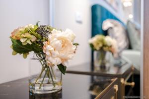 un jarrón lleno de flores blancas en una mesa en Bliss Land Luxury Apartments, en Gura Humorului