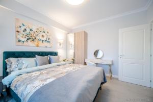 a bedroom with a blue bed with a painting on the wall at Bliss Land Luxury Apartments in Gura Humorului