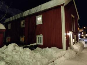 un edificio rojo con nieve alrededor por la noche en Sjøgata Riverside Rental and Salmon Fishing, en Mosjøen