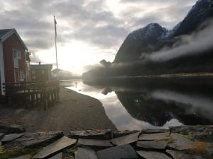un cuerpo de agua con un edificio y una montaña en Sjøgata Riverside Rental and Salmon Fishing en Mosjøen