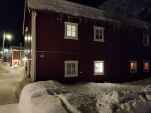 a red building with snow around it at night at Sjøgata Riverside Rental and Salmon Fishing in Mosjøen