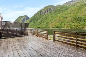 een houten terras met uitzicht op een rivier en de bergen bij Sjøgata Riverside Rental and Salmon Fishing in Mosjøen