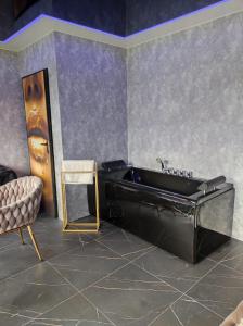 a bathroom with a black tub and a chair at Pensjonat Wrzos in Poznań