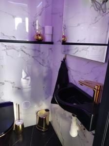 a bathroom with a black sink and a marble wall at Pensjonat Wrzos in Poznań