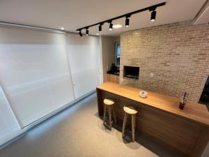 a bar with stools in a room with a brick wall at Recanto das Tartarugas - Guarujá in Guarujá