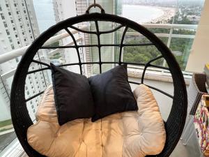 a swing chair with two pillows in a window at Recanto das Tartarugas - Guarujá in Guarujá