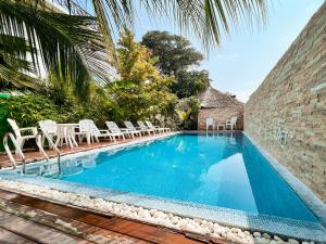 a swimming pool next to a brick wall with white chairs at PERLA Dhangethi in Dhangethi